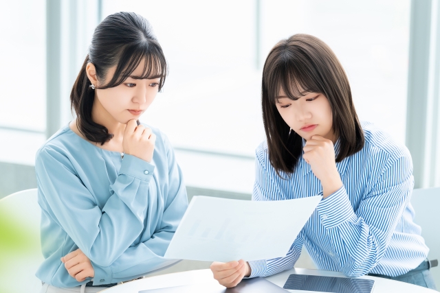 資料を見て矯正治療の方法を選ぶ二人の女性の画像