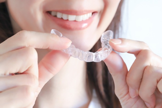 マウスピース型矯正装置を手に持つ女性の画像