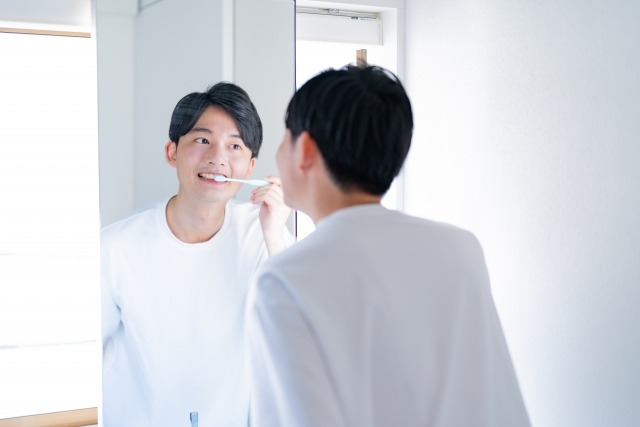矯正中の男性が鏡に向かって歯磨きをしている画像