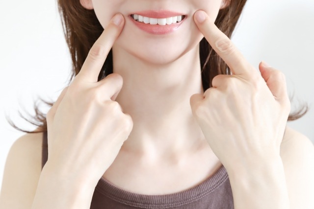 きれいな歯並びの女性が口元を指差している画像