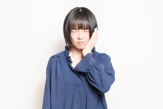 歯列矯正による痛みを感じている女性の画像