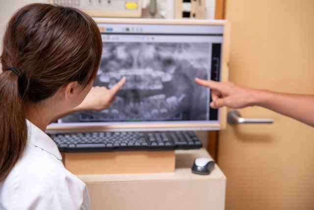 レントゲン写真を見ながら歯列矯正の説明をしている歯科衛生士の画像