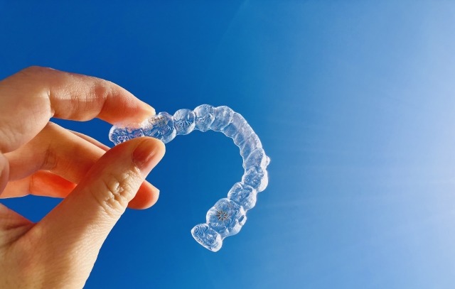 目立たない透明なマウスピース型矯正装置を手に持っている画像