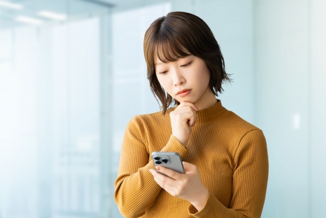 歯医者の口コミを見て不安を感じている女性の画像