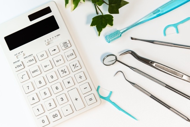 矯正治療の費用をイメージする電卓と歯科治療器具の画像