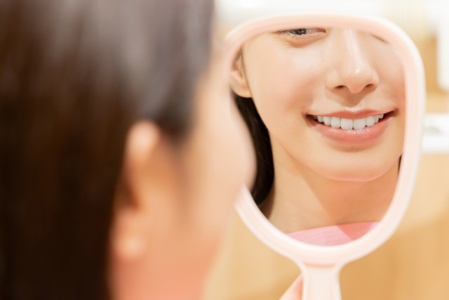 鏡で噛み合わせをチェックする女性