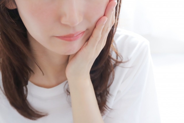 食いしばりによる顎の痛みを感じる女性